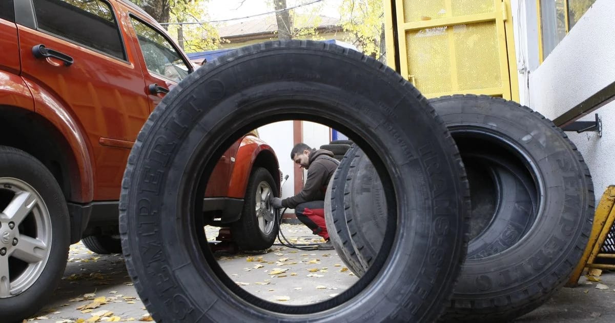 Un bărbat schimbă cauciucurile de vară ale mașinii cu cele de iarnă